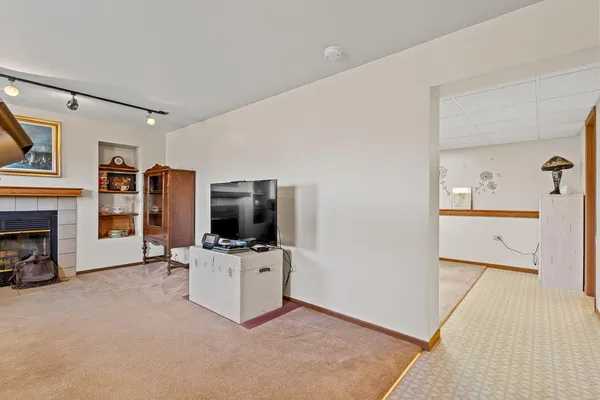 a view of a livingroom with a flat screen tv a fireplace and windows
