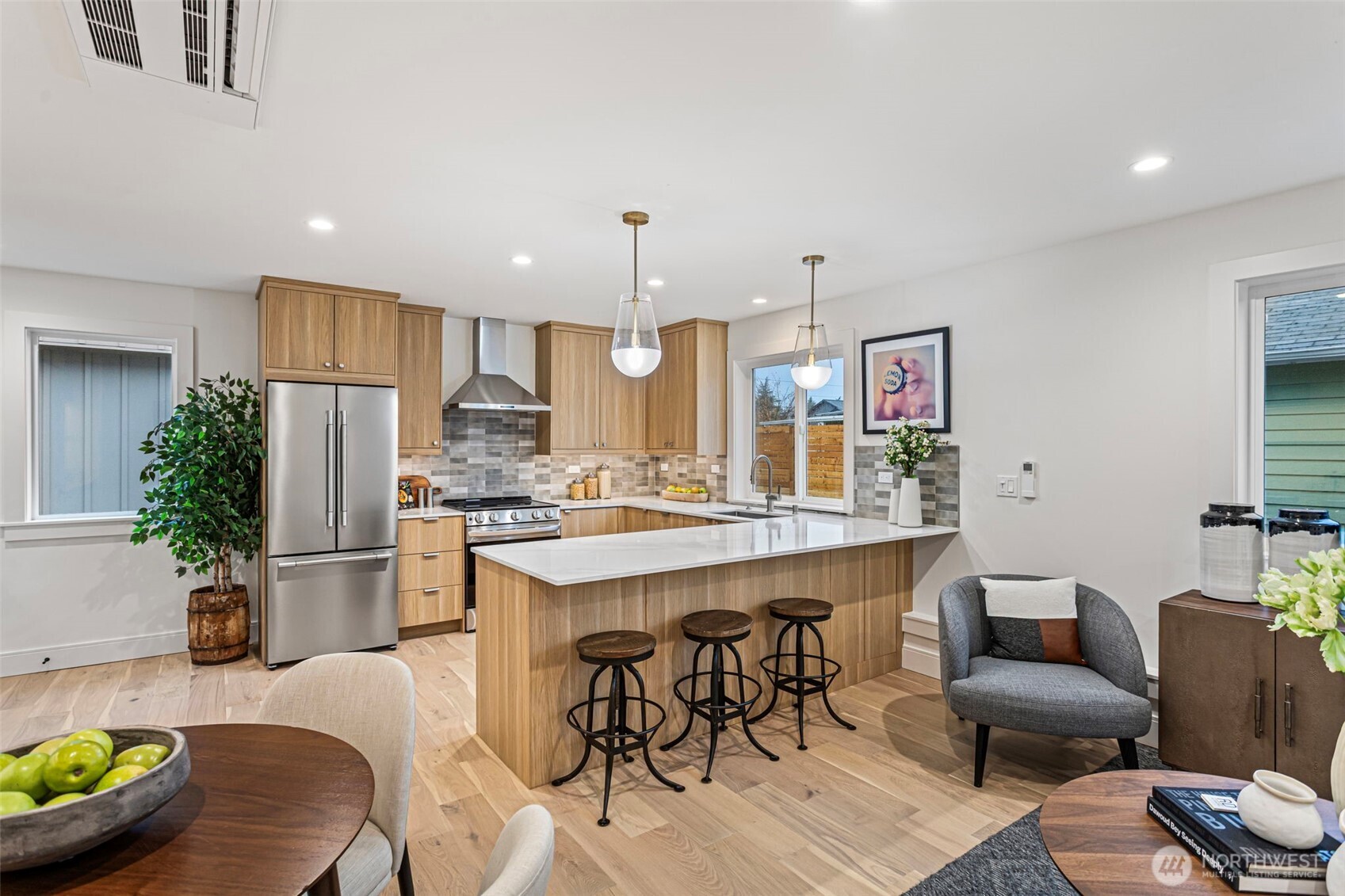 8003 25th Avenue Northwest Seattle, WA 98117 - Photo 4 of 25 a kitchen with stainless steel appliances kitchen island granite countertop a refrigerator a stove a sink a dining table and chairs with wooden floor