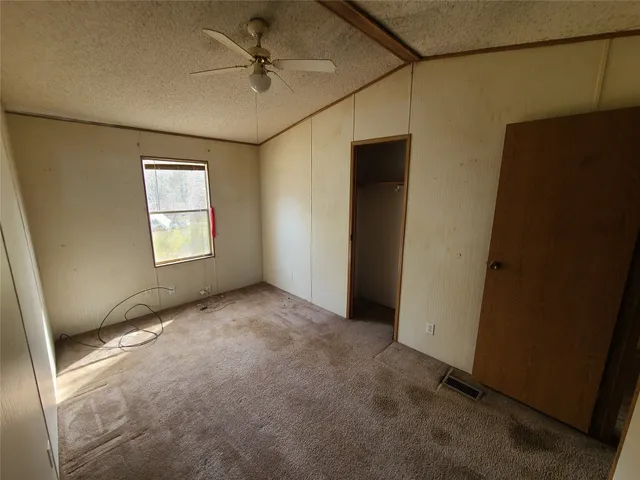 an empty room with windows and fan