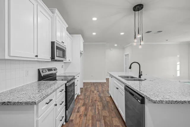 a kitchen with stainless steel appliances granite countertop a sink a stove and a wooden floors