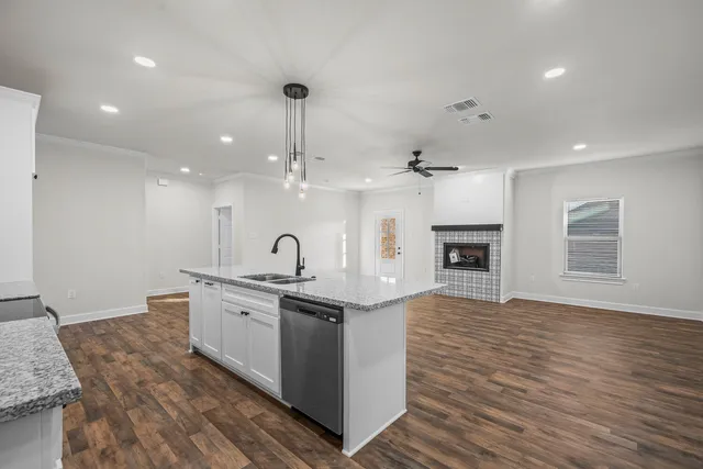 a large kitchen with stainless steel appliances granite countertop a sink a stove and a wooden floors