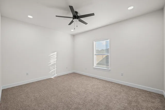 an empty room with a window and a ceiling fan