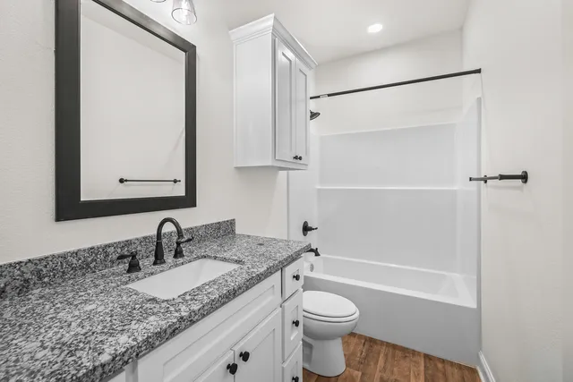 a bathroom with a granite countertop sink toilet and shower
