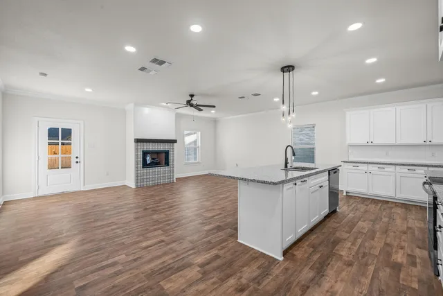 a kitchen with granite countertop a stove top oven a sink a counter space and cabinets