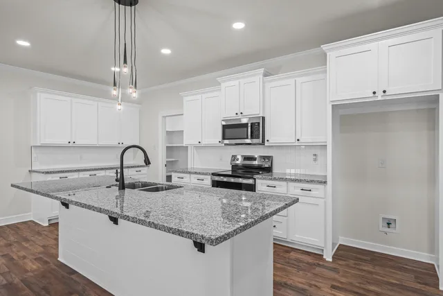 a kitchen with granite countertop a sink a center island stainless steel appliances and cabinets