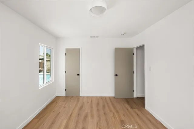 a view of an empty room with window and wooden floor