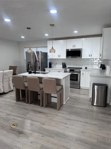 a kitchen with stainless steel appliances granite countertop a sink a microwave a refrigerator and white cabinets