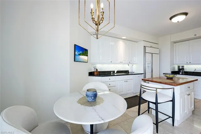 a kitchen with stainless steel appliances granite countertop a sink a stove a dining table and chairs