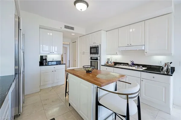 a kitchen with granite countertop a sink stove and white cabinets