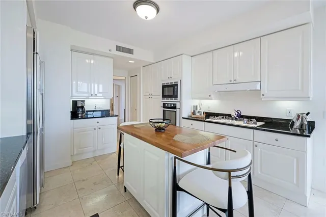 a kitchen with granite countertop a sink stove and white cabinets