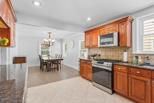 a kitchen with stainless steel appliances granite countertop a stove top oven a sink a dining table and chairs with wooden floor