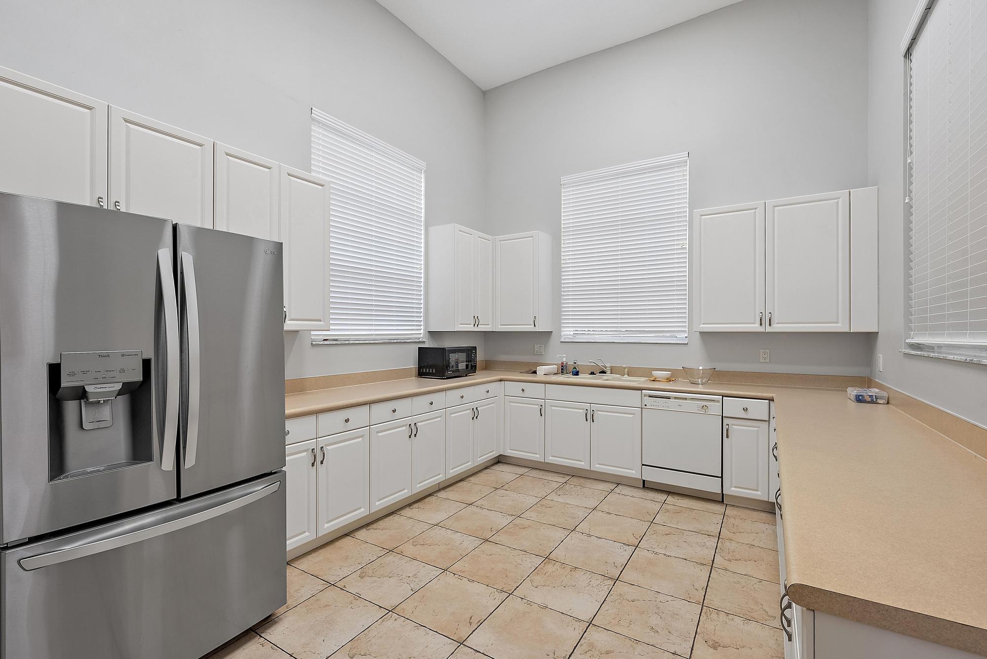 4237 East Main Street Jupiter, FL 33458 - Photo 16 of 21 a kitchen with granite countertop white cabinets and stainless steel appliances