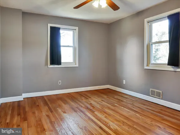 a view of an empty room with wooden floor and closet