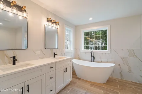 a bathroom with a double vanity sink mirror and bathtub