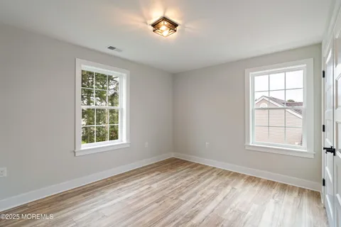 an empty room with wooden floor cabinet and windows