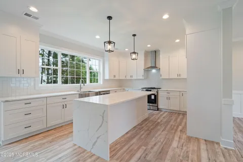 a large kitchen with kitchen island white cabinets and wooden floor