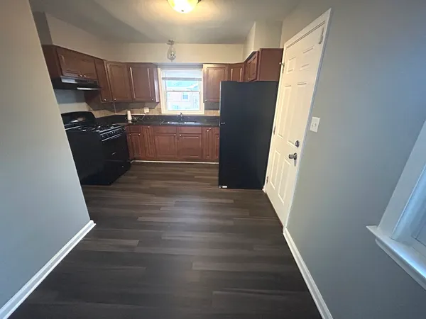 a kitchen with granite countertop a refrigerator a sink and white cabinets