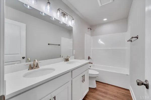 a bathroom with a double vanity sink toilet mirror and bathtub