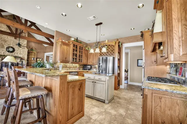a kitchen with kitchen island granite countertop lots of counter top space and refrigerator