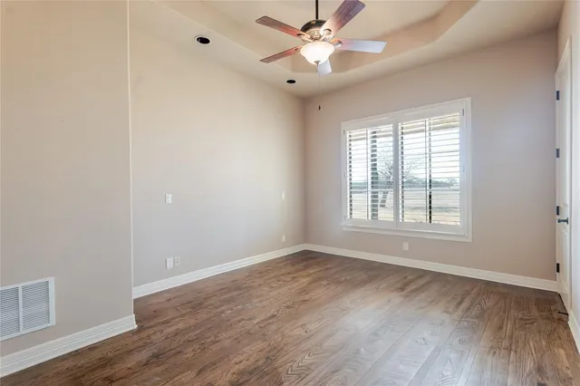 a view of empty room with wooden floor and fan
