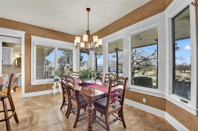 a view of a dining room with furniture large windows and a chandelier