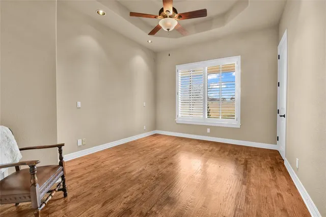 an empty room with wooden floor fan and windows