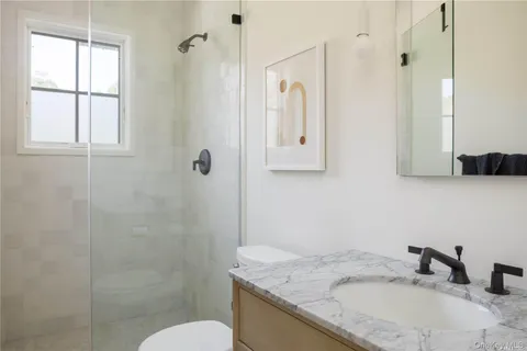 a bathroom with a granite countertop sink a mirror and a shower