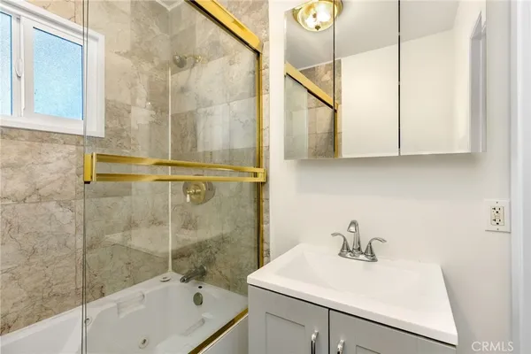 a bathroom with a sink and mirror with bathtub