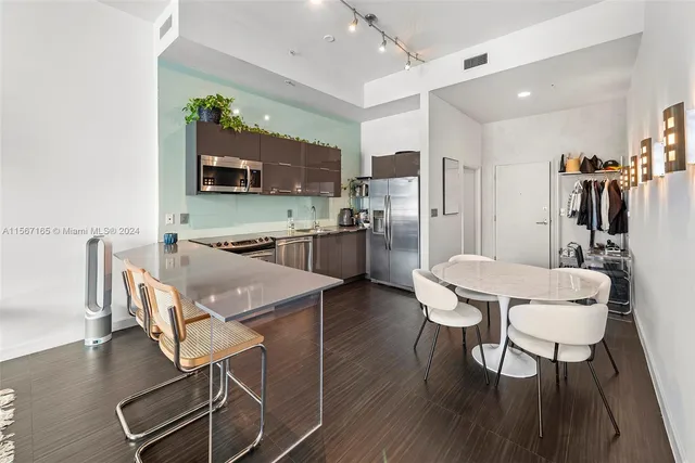 a kitchen with stainless steel appliances a dining table chairs and a refrigerator