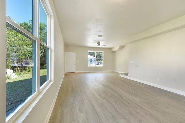 an empty room with wooden floor and windows