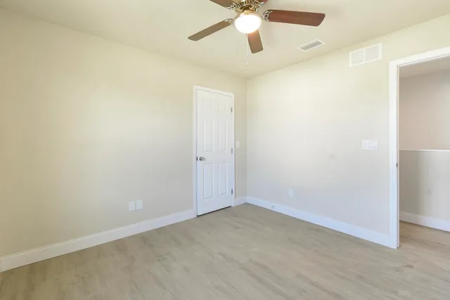 an empty room with a window and a ceiling fan