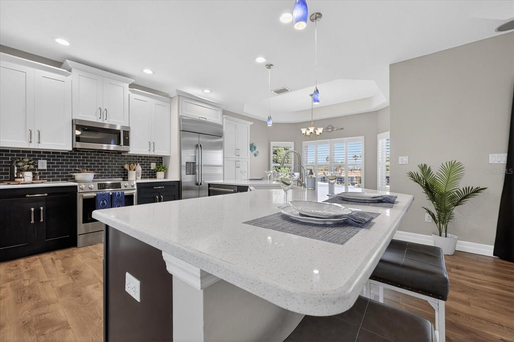 3339 Seaway Drive New Port Richey, FL 34652 - Photo 13 of 74 a kitchen with stainless steel appliances kitchen island granite countertop a stove a sink a refrigerator and white cabinets with wooden floor