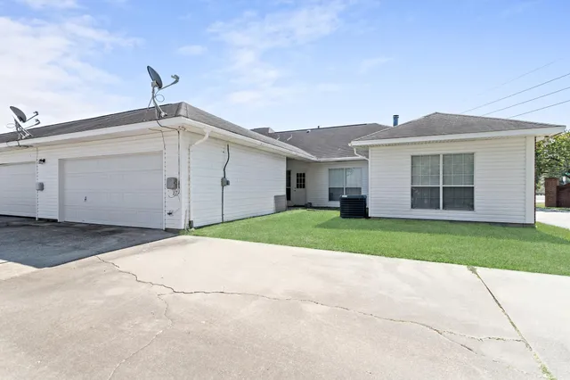 a view of a white house with a yard and a large tree