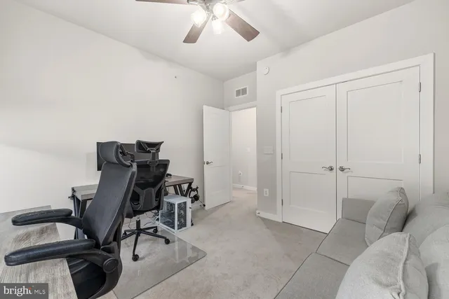 a view of a workspace with furniture and a ceiling fan