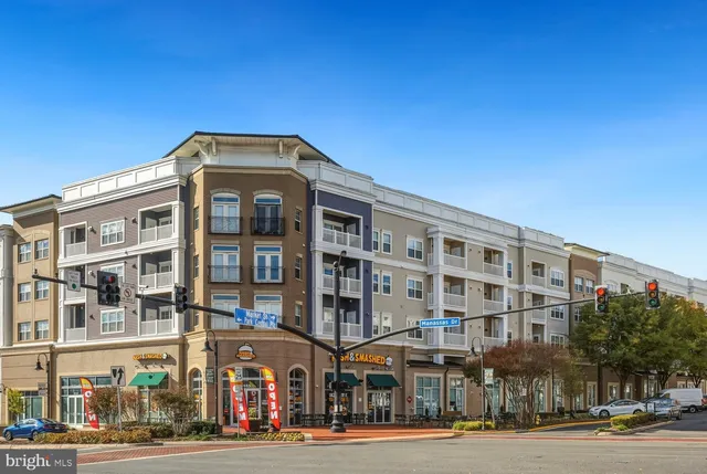 a front view of a building with lot of cars and trees