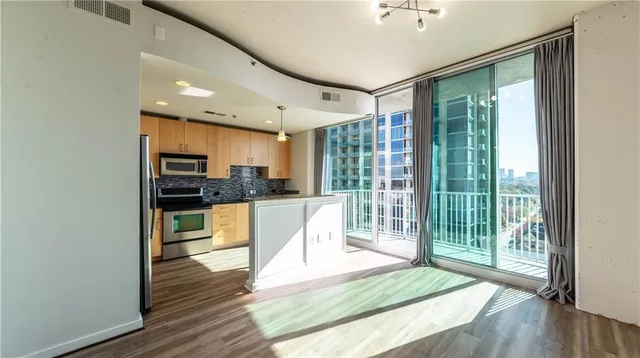 a kitchen with stainless steel appliances granite countertop a refrigerator a stove and a wooden floors