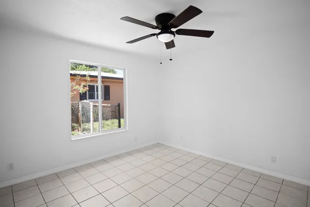 an empty room with windows and fan