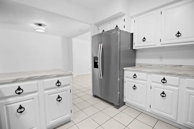 a kitchen with white cabinets and refrigerator