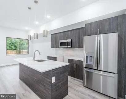 a kitchen with stainless steel appliances granite countertop a refrigerator a sink a stove a microwave and wooden floor