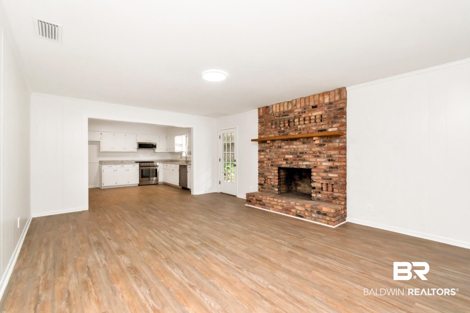 5217 Perin Road Mobile, AL 36693 - Photo 25 of 45 Spacious living area featuring a brick fireplace with wood mantel, wood-finish flooring, and a white ceiling