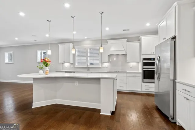 a kitchen with stainless steel appliances granite countertop a refrigerator a sink and wooden floors