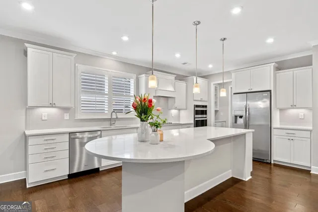 a kitchen with stainless steel appliances kitchen island granite countertop a sink a refrigerator a stove a dining table and chairs