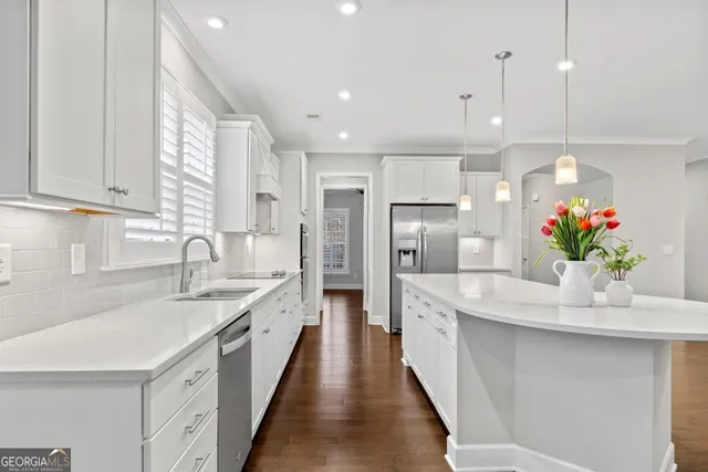 a kitchen with stainless steel appliances kitchen island granite countertop a sink and dishwasher with white cabinets