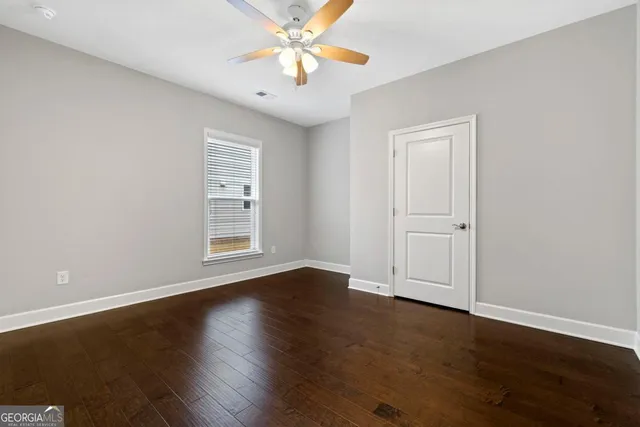 a view of an empty room with window and a ceiling fan