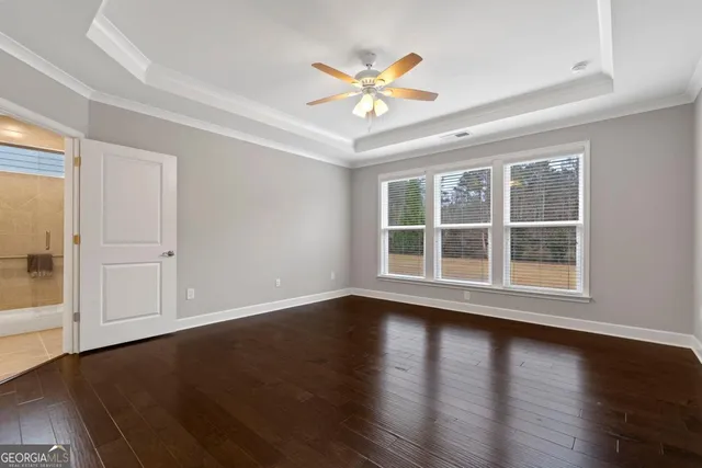 an empty room with wooden floor and ceiling fan