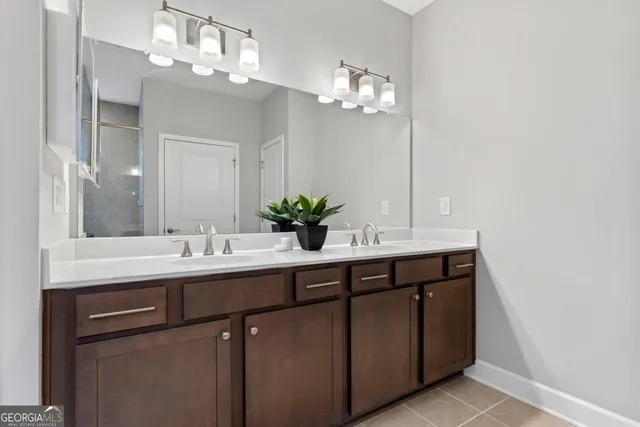 a bathroom with a granite countertop sink a mirror and shower