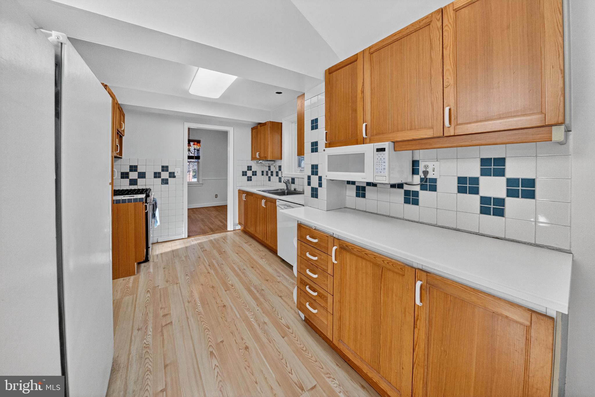 10018 Brookmoor Drive Silver Spring, MD 20901 - Photo 8 of 22 a kitchen with stainless steel appliances granite countertop a refrigerator a stove top oven and a sink with wooden cabinets