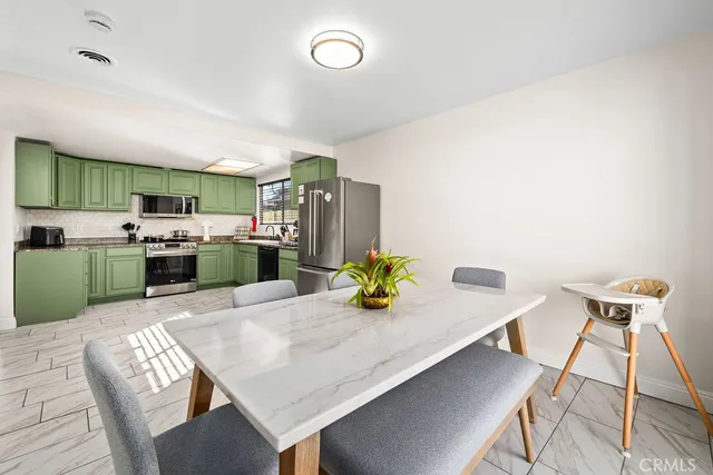 a kitchen with stainless steel appliances kitchen island granite countertop a table chairs and a refrigerator