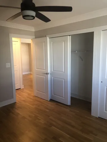 a view of empty room with wooden floor and fan