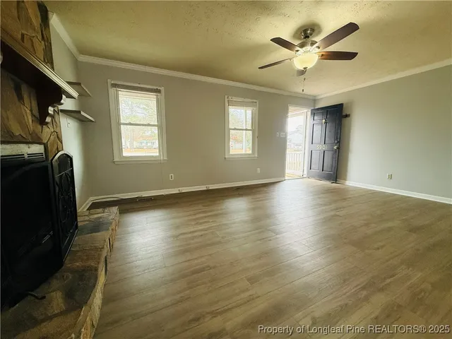 a view of an empty room with a window and wooden floor